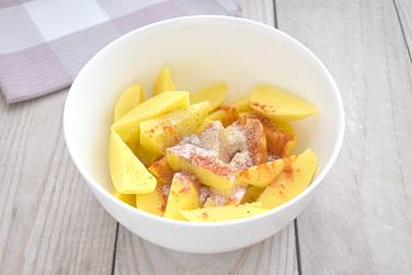 Картофельные ломтики посыпаем по вкусу солью, чёрным молотым перцем, паприкой, сушёным чесноком