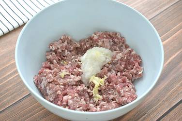 Мясной фарш перекладываем в миску и добавляем к нему натёртый лук и чеснок