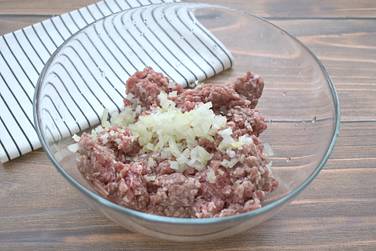 В широкую миску перекладываем мясной фарш и добавляем к нему лук, нарезанный маленькими кусочками