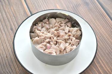 Отварное куриное мясо нарезаем маленькими кубиками, формируем следующий слой