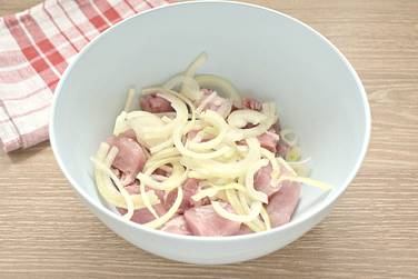 Лук нарезаем полукольцами или кольцами и перекладываем к мясу