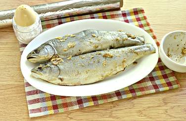 Гольца со всех сторон натираем по вкусу солью и приготовленной смесью из приправы и чеснока, включая внутренность