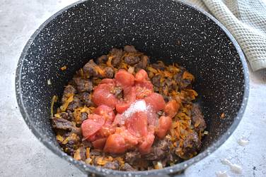 Очищенные от кожицы помидоры нарезаем кусочками и добавляем к мясу