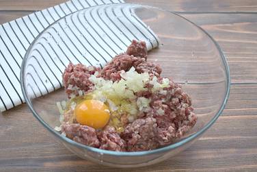 Далее в мясной фарш разбиваем куриное яйцо