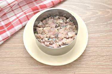 На картофельный слой помещаем нарезанную кубиками селёдку