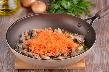 Морковку крупно натираем, выкладываем в сковороду с курицей и луком, перемешиваем