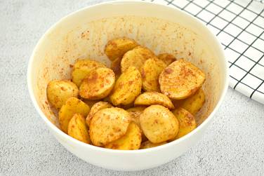 Картофельные дольки хорошо перемешиваем с маслом и специями