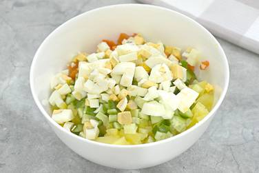 Шинкуем куриные яйца кусочками и добавляем в салат