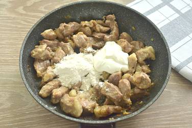 К обжаренным кусочкам мяса добавляем муку и сметану